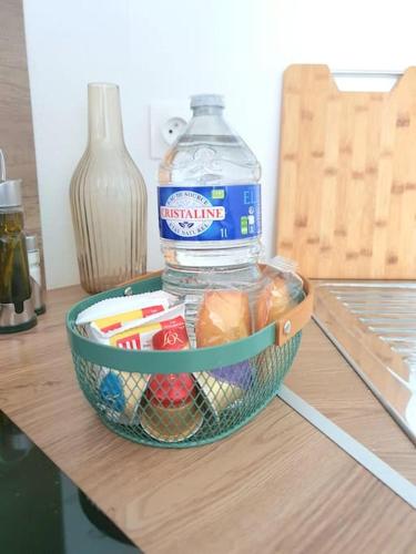eine Flasche Wasser und ein Korb mit Essen auf dem Tisch in der Unterkunft Duplex neuf - à 5 min de Nantes in Sautron
