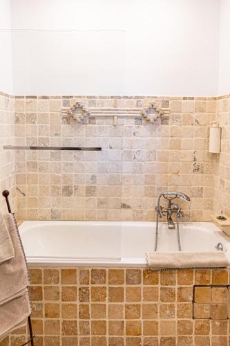 a bath tub in a bathroom with a tile wall at Maison Bournissac in Noves