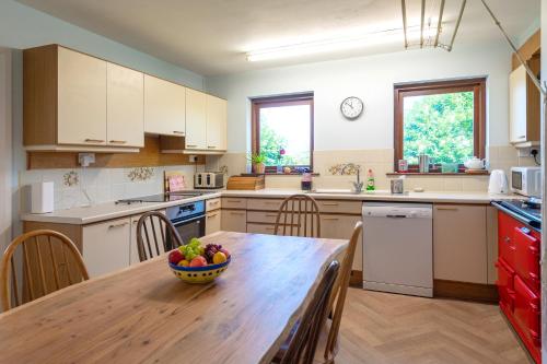 a kitchen with a wooden table with a bowl of fruit on it at Coastal Bungalow Near Marloes with Log Burner and Garden in Dale