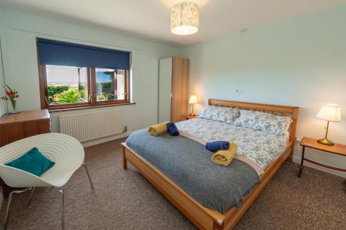 a bedroom with a bed and a chair and a window at Coastal Bungalow Near Marloes with Log Burner and Garden in Dale