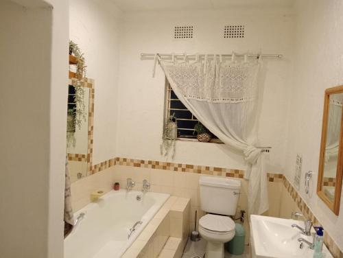 a bathroom with a tub and a toilet and a sink at Be Our Guest Near OR TAMBO International Airport in Boksburg