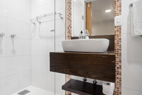 uma casa de banho branca com um lavatório e um chuveiro em Apartamento 4 Dorm e Piscina by Achei Gramado em Gramado