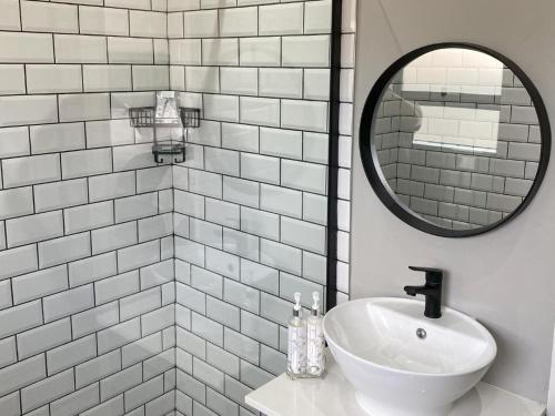 La salle de bains blanche est pourvue d'un lavabo et d'un miroir. dans l'établissement StaySure Guesthouse, à Alberton