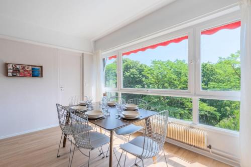 une salle à manger avec une table et des chaises et une grande fenêtre dans l'établissement Spacious 3 bedroom apartment & private parking!, à Lambersart