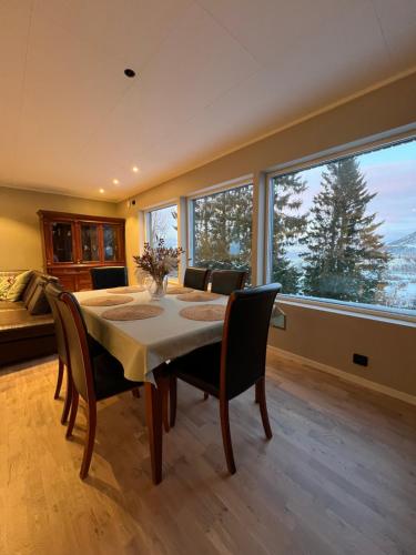 ein Esszimmer mit einem Tisch und Stühlen sowie einem großen Fenster in der Unterkunft Tromsø Arctic Villa with free parking in Tromsø