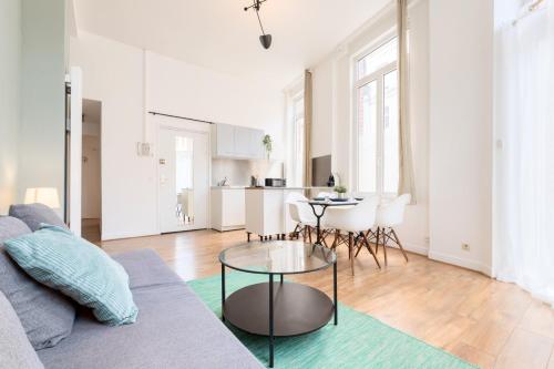 ein Wohnzimmer mit Sofa und Tisch in der Unterkunft Functional flat close to the station in Lille