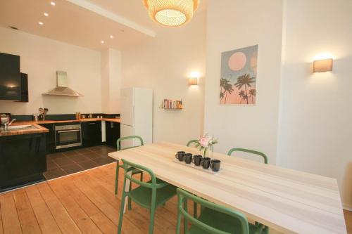 cocina con mesa de madera y sillas verdes en 2-bedroom flat + private car park., en Lille