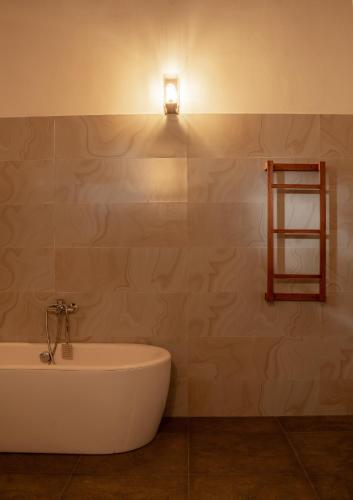 a bathroom with a tub and a light on the wall at Piyum Villa Kosgoda in Kosgoda