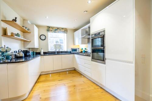 a kitchen with white cabinets and a wooden floor at The Brierley in York