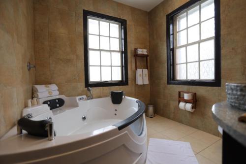 eine große weiße Badewanne im Bad mit zwei Fenstern in der Unterkunft Chakana Hotel Boutique Mariscal in Quito