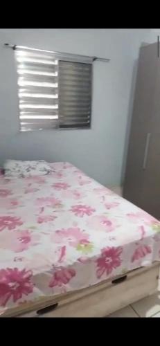 - un lit avec des fleurs roses dans une chambre dans l'établissement Casa Relax, à Caraguatatuba