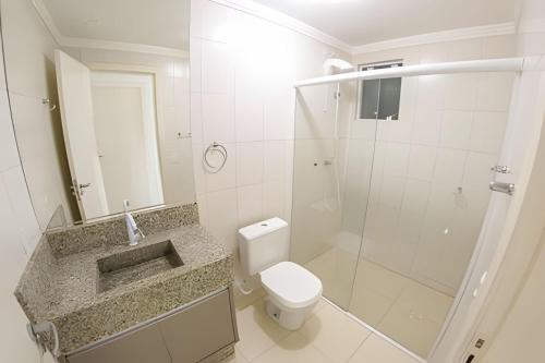 y baño blanco con aseo y ducha. en Apartamento com vista mar em excelente localização, en Bombinhas