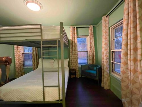a bedroom with a bunk bed and two windows at Chic 50s Time Capsule Downtown/OU Med/OK Capitol in Oklahoma City