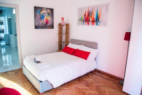 a small bedroom with a white bed with red pillows at Strambio28 in Milan