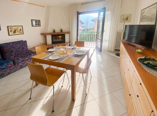 comedor con mesa con sillas y TV en Spacious apartment with terrace with mountain view en Moggio