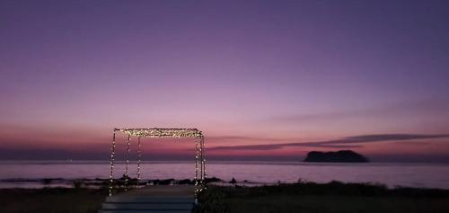 a string of lights in front of the ocean at sunset at The Beach Resort & Residence - SHA Plus in Pathiu