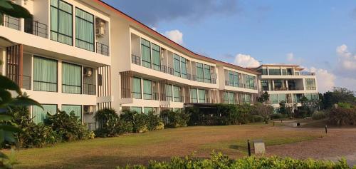 a large building with a yard in front of it at The Beach Resort & Residence - SHA Plus in Pathiu