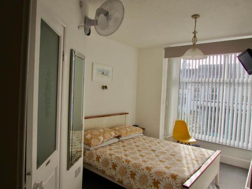 a bedroom with a bed and a window and a chair at Westward B&B in Newquay