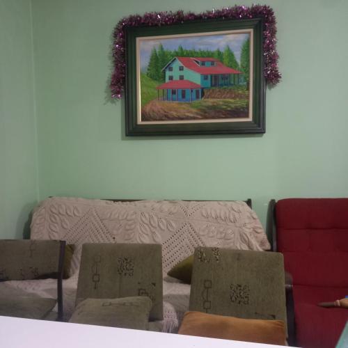 a painting of a house on the wall next to a couch at Planinska kuca Mikovica in Vrnjačka Banja