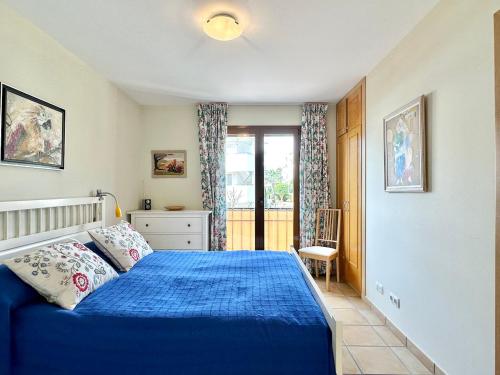 a bedroom with a blue bed and a window at Bonito Apartamento Con Piscina y Jacuzzi in L’Alfàs del Pi