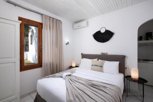 a bedroom with a bed with white sheets and a window at Acroterra - Easy Living in Alyki