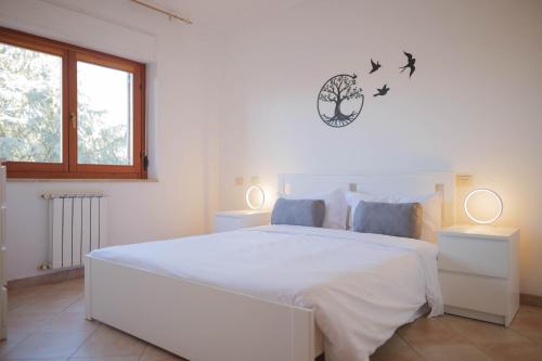 ein weißes Schlafzimmer mit einem großen weißen Bett mit zwei Lampen in der Unterkunft [Casa Ghandi] 20 min da Roma + Box Auto + Wi-Fi + Self Check-In in Monterotondo