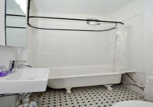 Baño blanco con bañera y lavamanos en Bright & Cozy 3BD Apartment In Mid West, en Nueva York