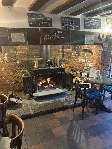 a fireplace in a restaurant with a table and chairs at The Half Moon Inn Rushall IP21 4QD in Pulham Saint Mary the Virgin