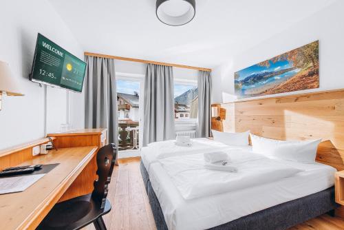 ein Hotelzimmer mit einem Bett, einem Schreibtisch und einem Computer in der Unterkunft Weidegg - Hotel Garni in Garmisch-Partenkirchen