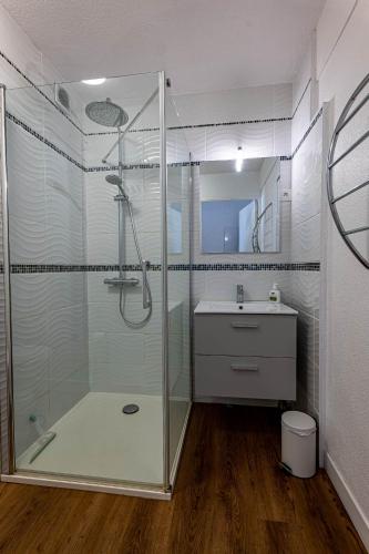 une salle de bain avec une douche en verre et un lavabo dans l'établissement Les conviviales Quartier théâtre gare, à Sète