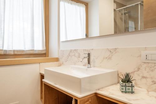 W łazience znajduje się biała umywalka i lustro. w obiekcie Chalet Falorie w mieście Cortina dʼAmpezzo