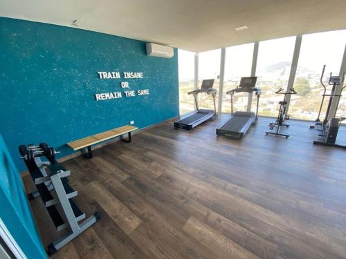 a gym with treadmills and a wall with a sign that reads train here at Bonito departamento en zona centrika in Monterrey