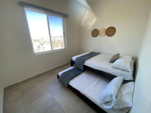 two beds in a room with a window at Bonito departamento en zona centrika in Monterrey