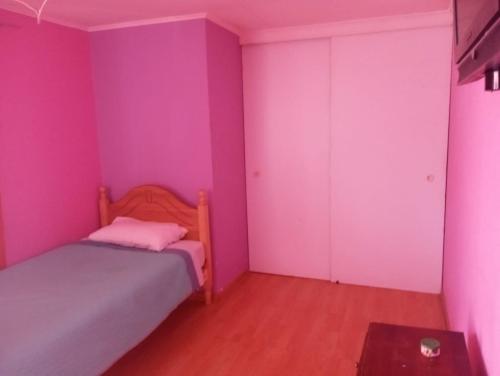 1 dormitorio con paredes rosas, 1 cama y 1 mesa en Hostal GoTravels, en Calama