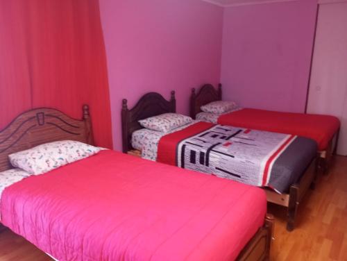Duas camas num quarto com paredes cor-de-rosa em Hostal GoTravels em Calama