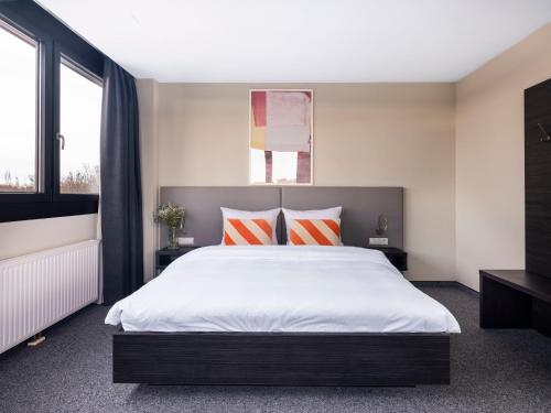 numa I Viktoria Apartments في ميونخ: غرفة نوم بسرير كبير ومخدات برتقالية وبيضاء