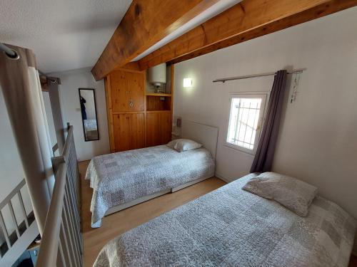 une chambre avec deux lits et une fenêtre dans l'établissement Le Bleu du Sud, à Gruissan
