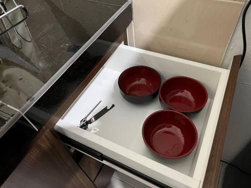 three red bowls on a white shelf in a drawer at Pusing Kampung Affordable Homestay in Pusing