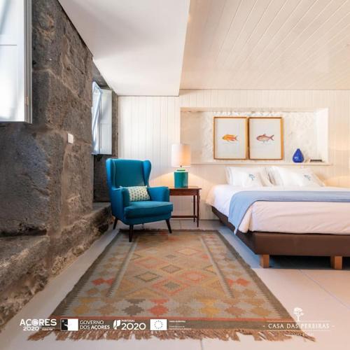 ein Schlafzimmer mit einem Bett und einem blauen Stuhl in der Unterkunft T2 Casa das Pereiras in Calheta de Nesquim