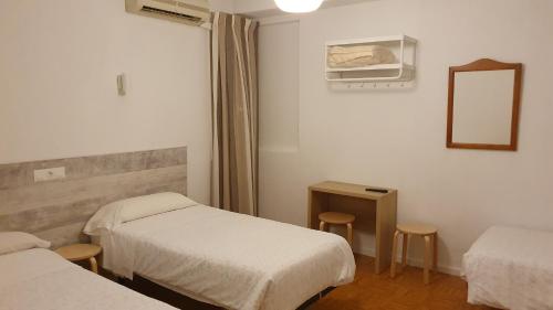 Habitación de hotel con 2 camas y espejo en Hostal Ginebra, en Madrid
