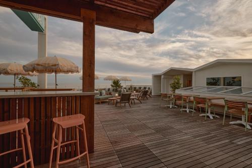 a deck with tables and chairs and a bar at Hotel Lucine in Galveston