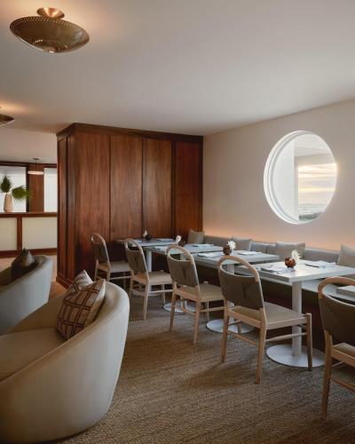 a dining room with tables and chairs and a circular window at Hotel Lucine in Galveston