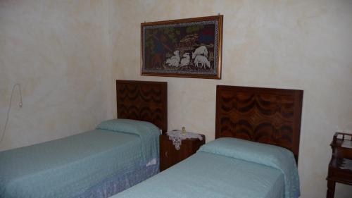 ein Schlafzimmer mit 2 Betten und einem Bild an der Wand in der Unterkunft B&B Nonna Peppina in Mògoro