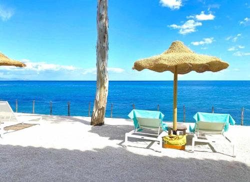 two chairs and an umbrella on the beach at Villa Azurella Il Paradiso è qui in Pula