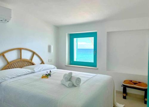 a bedroom with a large white bed with a window at Villa Azurella Il Paradiso è qui in Pula