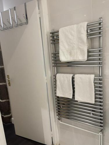 a towel rack in a bathroom with white towels at La Maison de l Echauguette Petit Dejeuner et Menage Offerts in Clermont-Ferrand