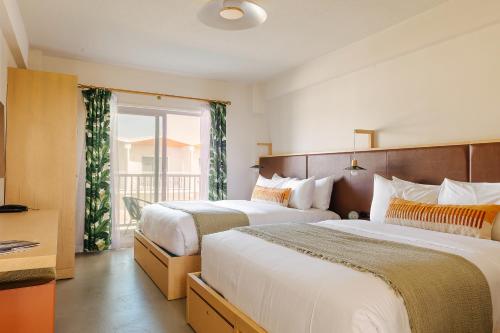 a hotel room with two beds and a balcony at Hotel Lucine in Galveston