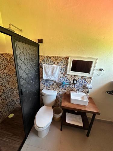 パレンケにあるCasa Koruのバスルーム(トイレ付)、壁にテレビが備わります。