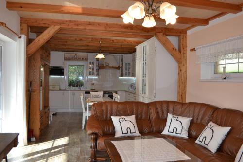 a living room with a brown leather couch and a kitchen at Ubytování Slezská Harta in Nová Pláň