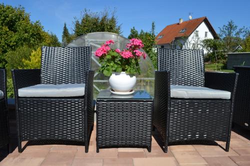 three chairs and a vase with flowers on a patio at Ubytování Slezská Harta in Nová Pláň